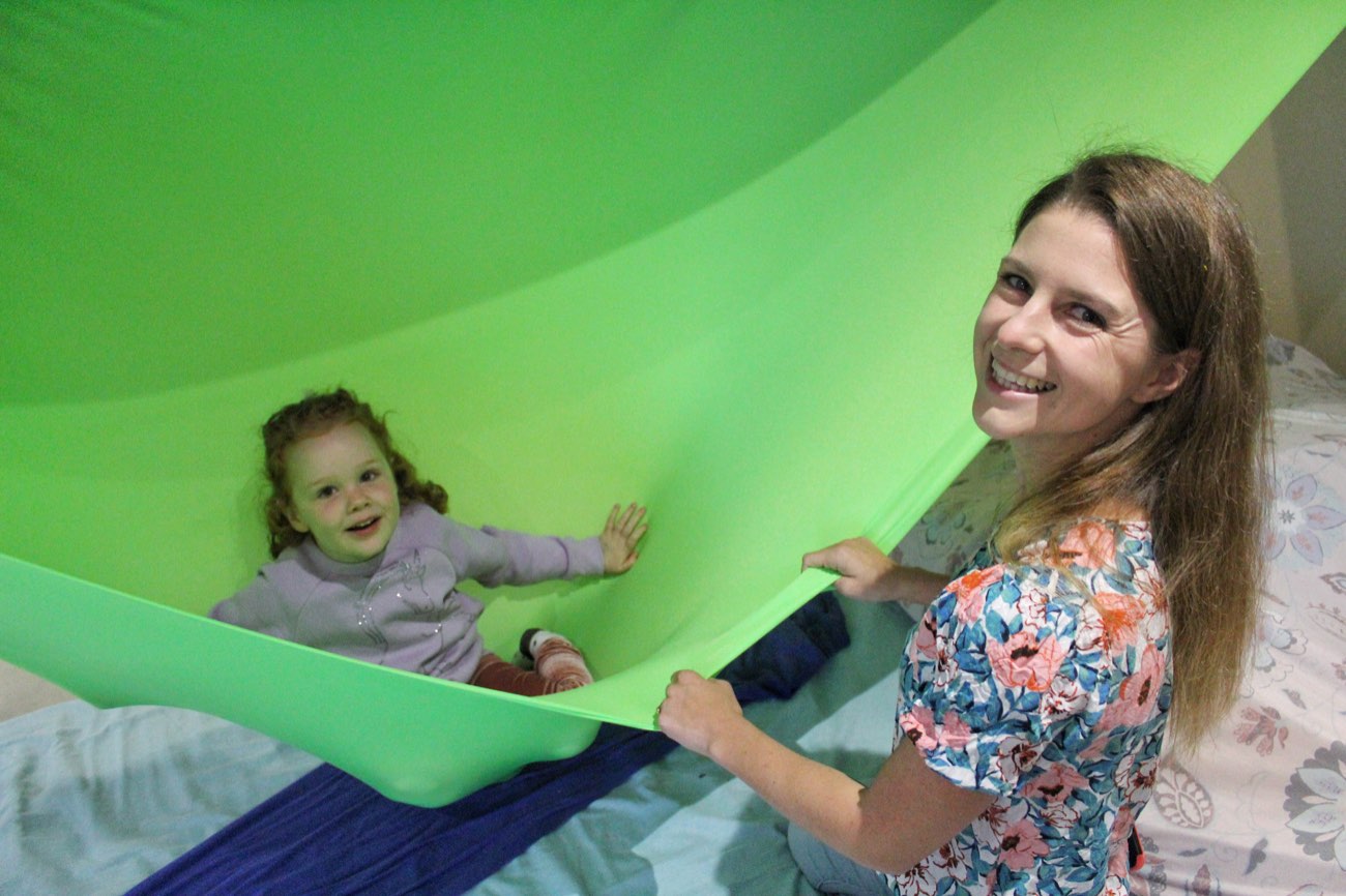 Occupational therapist and child playing together under a stretchy sensory parachute